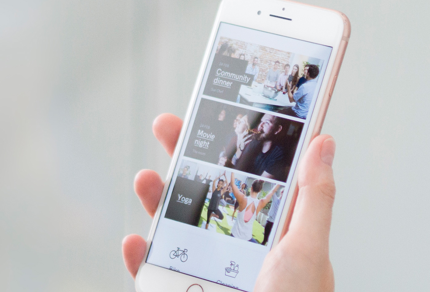 A closeup of a phone in a hand with opened UKO app showing three tiles about community engagement