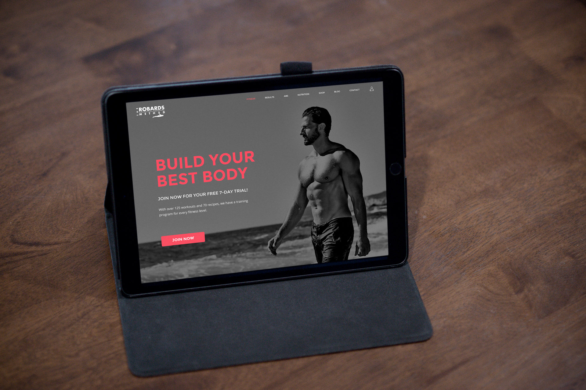 A laptop with the MBFW website showing the home page.